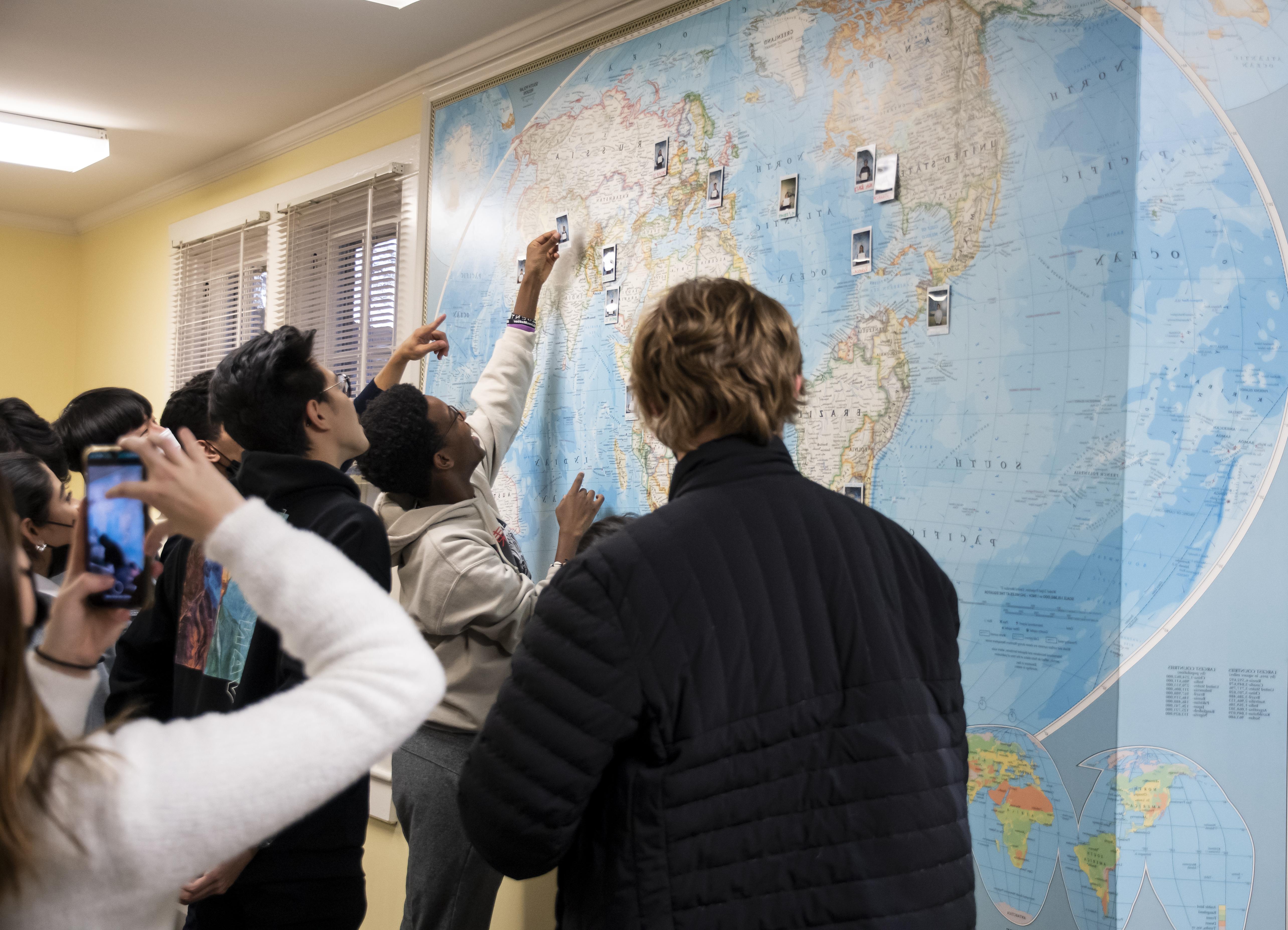 Members of WC's GEO look at a map with photos hanging on it